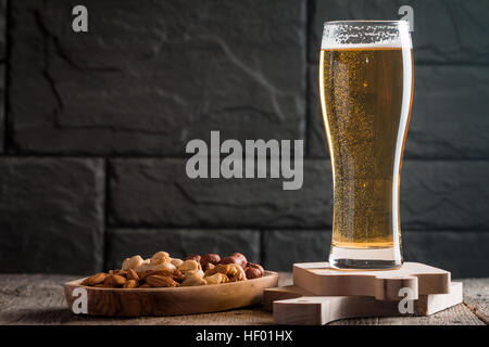 Bicchiere di birra chiara con bolle vicino muro nero Foto Stock