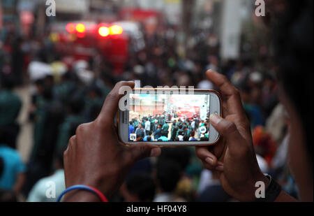 Dacca in Bangladesh. 24 dicembre, 2016. Un locale del Bangladesh sono le persone a fare un video sulle scene dopo il funzionamento e la tempesta un presunto militante nascondiglio in Dhaka sul dicembre 24, 2016 come un team dall'unità di lotta contro il terrorismo di Dhaka Metropolitan Police cordoned fuori da un edificio di tre piani nella capitale. Due militanti femmina lungo con due bambini si arrese ai poliziotti, 1 femmina e un militante teen si sono uccisi durante il raid della polizia per esplosione di giubbotto suicida al di fuori della loro den mentre agiscono per arrendersi alla cop. © Monirul Alam © Monirul Alam/ZUMA filo/Alamy Live News Foto Stock