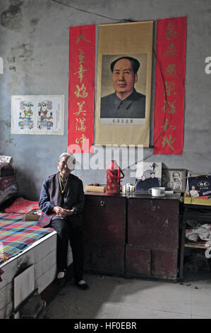 Yuncheng, Yuncheng, Cina. Il 26 dicembre, 2016. Yuncheng, Cina al 26 dicembre 2016: (solo uso editoriale. Cina OUT) .Qin Yuling, un 97-anno-vecchia donna, si siede nella sua casa decorata con il Presidente Mao Zedong il ritratto. È il 123º anniversario del Presidente Mao Zedong il compleanno su dicembre 26th, 2016. Il presidente Mao Zedong il ritratto può essere visto in molti cinesi la vita quotidiana delle persone. © SIPA Asia/ZUMA filo/Alamy Live News Foto Stock