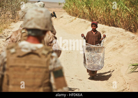 Marines con Mobile Assault Platoon 4, armi Company, 1° Battaglione, XXV Reggimento Marino passa un ragazzo afgano spingendo una carriola mentre su una pattuglia nella porzione meridionale del distretto di Washir, provincia di Helmand, Ott 4. I marines di armi Co. sono stati essi stessi di familiarizzare con il confine meridionale della Task Force Belleau legno spazio di battaglia nel centro di Helmand dato che arrivano in Afghanistan nel mese di settembre. Di pattuglia con la Nuova Inghilterra la propria 111004-M-PH073-117 Foto Stock