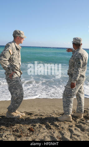 Il personale dell'esercito Sgt. Noe PerezMartir, un ingegnere assegnato al quarantesimo divisione di fanteria, Joint Task Force Guantanamo, punti mentre si raccontano gli eventi della Giornata del Ringraziamento con Pvt. Ryan Curtis, la polizia militare assegnato alla 66ma la polizia militare Company, JTF GTMO, al mulino a vento Beach, U.S. La stazione navale di Guantanamo Bay a Cuba, Dic 11, 2013. I due hanno contribuito due vittime separatamente che erano in difficoltà nell'acqua in pochi secondi di ogni altro. Soldati a filamento salva nuotatori 131211-Z-IB888-012 Foto Stock