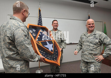 Col. Roger E. Williams Jr., commander, 145Airlift Wing, e il tenente Col. Robert Andrews, capo dell ala Intelligence, presente una scatola di ombra, fatta dall'onorevole Andrews per una molto sorpreso di Brig. Gen. Tony McMillan, Marzo 25, 2013. McMillan fu Comandante del 145Airlift Wing da Dic. 22, 2004 a settembre 30, 2012. Badge professionali sono stati raccolti dagli aviatori da 145North Carolina Air National Guard. Una piccola replica di C-130 Hercules aeromobile numero di coda 1458 è stata inoltre inclusa come un omaggio a MAFFS-7, che si è schiantato durante il suo comando. Stati Uniti e bandiere N.C. ultimo volato oltre il basamento mentre il Brig. Gen. Foto Stock