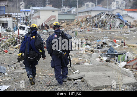 I membri del CA-TF2 a piedi attraverso le macerie loro autobus dopo la ricerca per le vittime dello tsunami in Ofunato, Giappone, durante il mese di Marzo 15, 2011. Membri del Los Angeles cerca e squadra di salvataggio, Task Force 2 stanno rispondendo alla recente emergenza nazionale in Giappone a causa del terremoto fornendo cure necessarie, al salvataggio delle tecniche e degli strumenti. Flickr - DVIDSHUB - Operazione Tomodachi immagine (2 di 52) Foto Stock