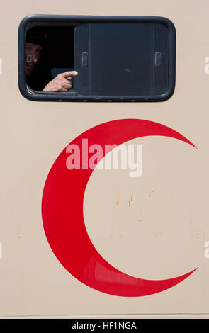 Un esercito nazionale afghano soldato con il 215th Corps guarda fuori dalla finestra di una ambulanza a Camp Bastion, provincia di Helmand, Afghanistan, Ottobre 14, 2013. Sei pazienti della clinica medica presso il Camp Shorabak, compresi i militari e civili, sono state trasferite ad Herat, marcatura questo evento come la prima volta che un C-130 Hercules aereo era stato utilizzato per il medico afghano di trasporto. (Gazzetta Marine Corps Foto di Sgt. Tammy K. Hineline / rilasciato) ANA trasporta i pazienti da C-130 131014-M-RF397-069 Foto Stock