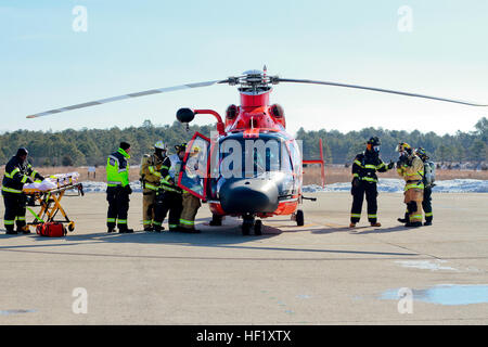 Stati Uniti Air Force protezione antincendio specialisti del New Jersey Air National Guard il 177th Fighter Wing lungo con emergency medical tecnici provenienti da sud Jersey Transportation Authority aviatori estratto da un U.S. Coast Guard MH-65D Delfino elicottero durante un incidente aereo esercizio presso la guardia costiera Stazione aria di Atlantic City, 11 febbraio, 2014. L'esercizio, che è un requisito annuale per la stazione aerea di Atlantic City, ha coinvolto la Coast Guard, Federal Aviation Administration, South Jersey Transportation Authority i Vigili del Fuoco e 177th Fighter Wing dei Vigili del Fuoco. (U.S. Air National gua Foto Stock