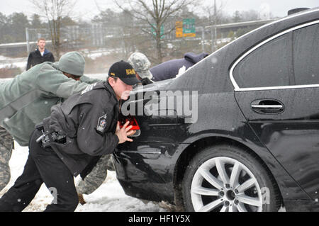 Pfc. Lorenzo Garrick, 113Supporto brigata, e vice Erik Seda, riattivazione dello sceriffo della contea di Office, spingere una macchina fuori del fosso lungo una rampa di uscita in Raleigh, North Carolina, Feb 13, 2014. La Carolina del Nord la Guardia Nazionale è stata assistere i funzionari di polizia sul loro pattuglie in tutto lo stato. (U.S. Esercito nazionale Guard foto di PFC. Lisa vitigni, 382 Affari pubblici Distacco/RILASCIATO) NC National Guard per assistere la Carolina del Nord Divisione nella gestione delle situazioni di emergenza durante la tempesta di neve Pax 140213-Z-EH515-119 Foto Stock