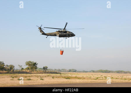 Una U. S. esercito UH-60 Blackhawk elicottero dall'1-228esimo reggimento aviazione decolla da Soto Cano Air Base, in Honduras con un secchio di acqua attaccato a combattere un incendio su un crinale in Comayagua, Honduras. Il fuoco ha proposto una minaccia di distruggere le case e tagliare una strada di accesso ad un villaggio locale. Entro un ora di ricezione della chiamata, gli elicotteri oggetto di pratiche di dumping su si ottengono 6.180 galloni di acqua sul rogo per attenuare il pericolo. (Foto di U. S. Air National Guard Capt. Steven Stubbs) Joint Task Force-BravoE28099s 1-228esimo reggimento aviazione contribuisce a proteggere il paese onduregno da fuoco 140402-Z-BZ170-0 Foto Stock