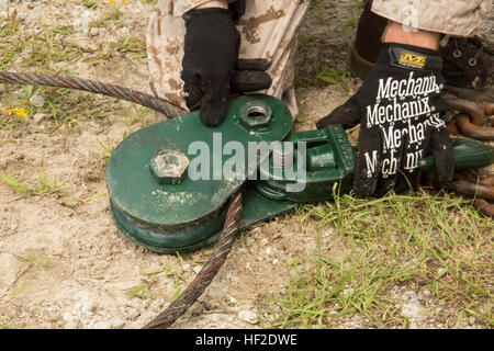 Un Marine con logistica di combattimento del reggimento di 2, 2° Marine Logistics Group imposta un cavo a una puleggia durante il recupero del veicolo a bordo training camp Johnson, N.C., 19 Agosto, 2014. Auto-recupero del MC-28 7-ton carrello coinvolti di aggancio del veicolo con il verricello ad un sistema di pulegge e quindi di attivare il verricello per tirare fuori il veicolo. Il Pit, Marines treno per recupero veicolo 140819-M-WI309-045 Foto Stock