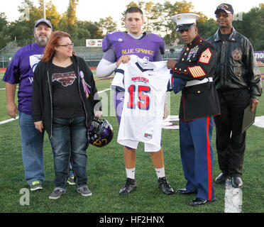 Sergente Maggiore Johnnie Hughes, Marine Corps stazione di reclutamento di Kansas City sergente maggiore, e il Sindaco di Carson Ross, molle blu sindaco, presente Jaycee Pummill, molle blu High School senior ling snapper e un 2015 Semper Fidelis All-American selectee ciotola con il suo jersey a Peve Stadium come i suoi genitori, Dan e Cindy Pummill, guardare su Ottobre 3, 2014. Pummill era l'unico giocatore scelto da Missouri Kansas o a partecipare a questo anno di bocce. Egli è inoltre classificato undicesimo assoluto per scattare in kohlskicking.com. snapping Molle blu High School long snapper presentato jersey per 2015 Foto Stock