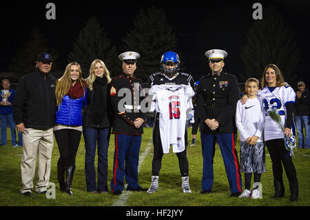 Drew Berger (centro), all'interno un linebacker per il Coeur d'Alene High School Vichinghi e 17-anno-vecchio nativo di Coeur d'Alene, Idaho, sorge accanto alla sua famiglia e riceve la sua Semper Fidelis ciotola All-American jersey da Sgt. Alex angolo (sinistra), un locale addetto alla selezione del personale marittimo e il cap. Ryan Sahlberg (a destra), Operations Officer del Marine Corps stazione di reclutamento di Seattle, prima di una partita contro il lago di Città Alta Scuola Timberwolves al Coeur d'Alene High School di Coeur d'Alene, Ottobre 17, 2014. Berger è la suola Idaho player tra circa 100 studenti atleti provenienti da tutta la nazione selezionata Foto Stock