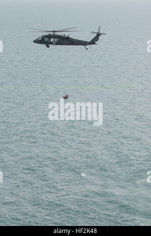 La compagnia F, 2-147th Assault Helicopter Battalion, conduce un addestramento di recupero del personale sul Golfo Arabico, utilizzando un paranco per sollevare un nuotatore in un cesto, simulando un'operazione medevac vicino alla base navale del Kuwait. Foto Stock