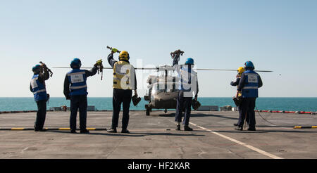 I membri dell'equipaggio con la British Royal Navy dimostrare che essi hanno staccato di catene e blocchi utilizzati per legare la UH-60 Black Hawk, con equipaggio 34a combattere la Brigata Aerea, al ponte della Flotta Reale ausiliari di Lyme Bay, Ottobre 22, 2014. Personale di volo con la società B e C Company, 2-147th elicottero d'assalto battaglione condotta deck qualifica di atterraggio sul Golfo Arabico per prepararli a terra su questo tipo di nave in futuro. (Minnesota esercito nazionale Guard foto di Spc. Jess Nemec/RILASCIATO) Deck qualifica di atterraggio 141022-Z-OX391-084 Foto Stock