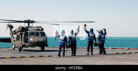 Membri della British Royal Navy dimostrare che essi hanno staccato di catene e blocchi utilizzati per legare la UH-60 Black Hawk, con equipaggio militari impegnati in Kuwait con la trentaquattresima combattere la Brigata Aerea, al ponte della Flotta Reale ausiliari di Lyme Bay sul Golfo Arabico ott. 22, 2014. Personale di volo dalla società B e C Company, 2-147 assalto battaglione elicottero sono stati valutati per la qualificazione a terra sul ponte di una nave. (Minnesota esercito nazionale Guard foto da 1Lt. Holly Elkin/RILASCIATO) Deck qualifica di atterraggio 141022-Z-QD498-439 Foto Stock