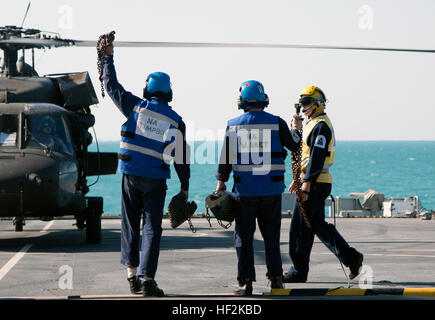 Membri della British Royal Navy dimostrare che essi hanno staccato di catene e blocchi utilizzati per legare la UH-60 Blackhawk, con equipaggio militari impegnati in Kuwait con la trentaquattresima combattere la Brigata Aerea, al ponte della Flotta Reale ausiliari di Lyme Bay sul Golfo Arabico ott. 22, 2014. Personale di volo dalla società B e C Company, 2-147 assalto battaglione elicottero sono stati valutati per la qualificazione a terra sul ponte di una nave. (Minnesota esercito nazionale Guard foto da 1Lt. Holly Elkin/RILASCIATO) Deck qualifica di atterraggio 141022-Z-QD498-505 Foto Stock