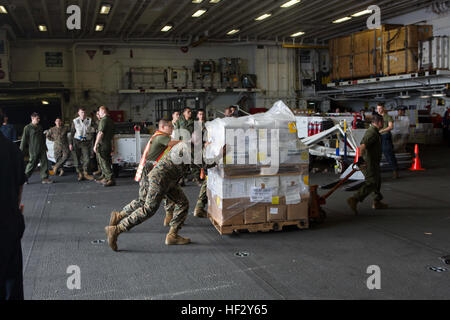 Stati Uniti Marines con il trentunesimo Marine Expeditionary Unit portare aiuti alimentari e forniture durante un rifornimento in mare (RAS) sulla USS Bonhomme Richard (LHD 6), al mare, Feb 16, 2015. Un RAS è come navi della marina militare di ricevere le merci e i materiali di consumo mentre fuori in mare. (U.S. Marine Corps photo by Lance Cpl. Richard Currier/RILASCIATO) Marines e marinai di condurre a una ricostituzione in mare 150216-M-UH847-038 Foto Stock