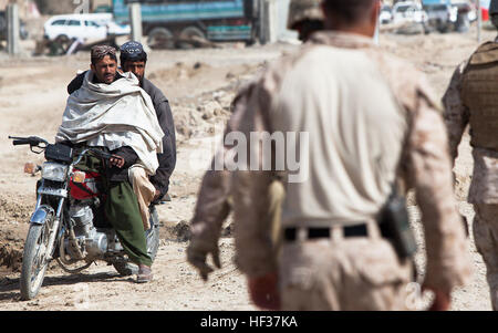 I locali del quartiere Garmsir, provincia di Helmand, Afghanistan, guardare un gruppo di noi diplomatici a piedi per il quartiere Garmsir centro con una cauzione di entourage di Marines, esercito nazionale afghano soldati e polizia nazionale afgana, Feb. 21, a partecipare a una sicurezza e stabilità shura con funzionari afghani. Il noi diplomatici incluso Karl W. Eikenberry, l ambasciatore statunitense in Afghanistan, e senatori Bob tappatrice, Tennesee; Bernie Sanders, Vermont; Joe Manchin, West Virginia; e Christopher Coon, Delaware. Rappresentanti afghani incluso Mir Hamza, il direttore nazionale della sicurezza; Gulab Mangal, il p Foto Stock