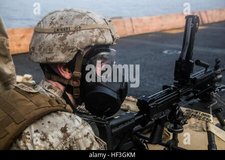 Golfo di Aden (Luglio 14, 2015) DEGLI STATI UNITI Lancia Marine Cpl. Tyler Knotts indossa la sua maschera a gas prima di sparare un M240B mitragliatrice su bersagli sul ponte di volo dell'assalto anfibio nave USS Essex (LHD 2). Knotts è una macchina gunner con Lima Company, Battaglione Team di atterraggio 3° Battaglione, 1° Reggimento Marine, xv Marine Expeditionary Unit. Xv MEU è imbarcata sull'Essex anfibio gruppo pronto e viene distribuito per mantenere la sicurezza regionale negli Stati Uniti Quinta Flotta area di operazioni. (U.S. Marine Corps foto di Cpl. Elize McKelvey/RILASCIATO) U.S. Marines fuori fuoco di mitragliatrici 150714-M-JT438-042 Foto Stock