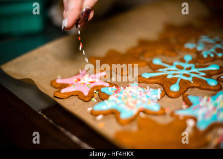 Mano Womans decorare i biscotti con lo zucchero. Rendendo Gingerbread Cookies serie. Foto Stock