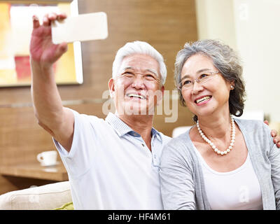 Felice asian coppia senior prendendo un selfie utilizzando il telefono cellulare. Foto Stock
