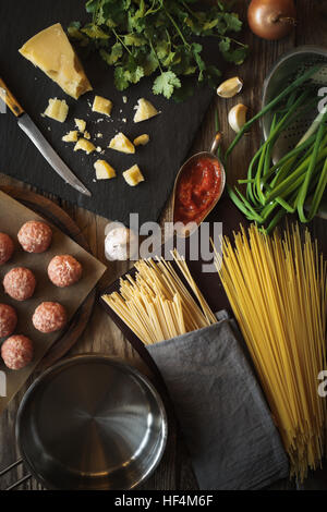 Gli ingredienti per cucinare gli spaghetti, Polpette con formaggio ed erbe fresche verticale vista superiore Foto Stock