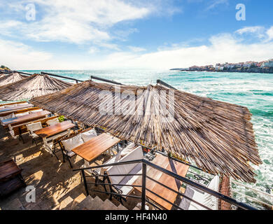 Ristorante tavolo con panca e cuscini bianchi in riva al mare in città vecchia Foto Stock