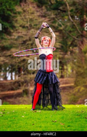 Giovane bella donna in costume di circo gioca con hula hoop nel