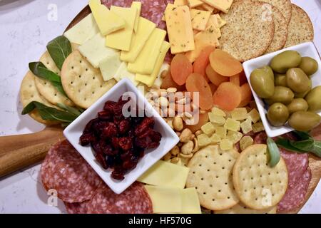 Un piatto di cibo preparare come antipasto per una festa costituito da formaggio, cracker, frutta secca, noci e olive Foto Stock