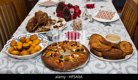 Tabella set parzialmente per un tradizionale portoghese la notte di Natale una cena con arrosto di tacchino e dessert come Frittelle di zucca, torta e rabanada Foto Stock