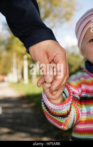 Il padre e i suoi tre-anno-vecchio figlia tenendo le mani Foto Stock