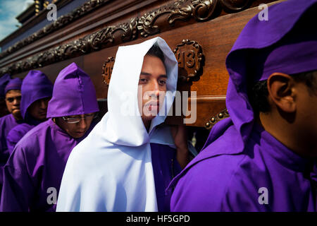 Antigua Guatemala - 16 Aprile 2014: uomo che indossa il viola e vesti bianche, portante un galleggiante (EUN) durante le celebrazioni pasquali. Foto Stock