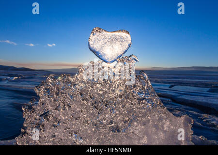 Sole al tramonto risplende attraverso il gelido cuore sulla tessitura trasparente glaçon nel lago Baikal. Foto Stock