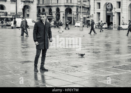 Uomo che cammina in piazza delle piogge in Europa Foto Stock