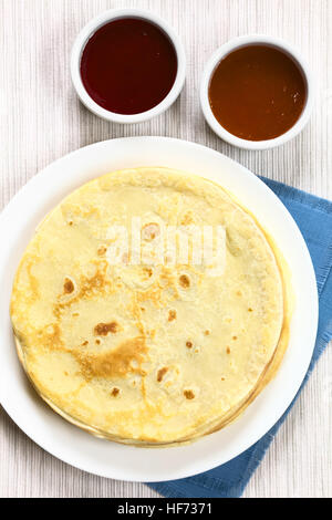 Appena sfornati crepes impilati sulla piastra con fragola e confettura di albicocca, fotografato il sovraccarico con luce naturale (messa a fuoco selettiva) Foto Stock