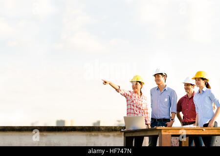 Multietnica variegato gruppo di ingegneri o business partner a livello di sito in costruzione, rivolta verso lo spazio di copia su sky durante il tramonto, ingegneria industr Foto Stock