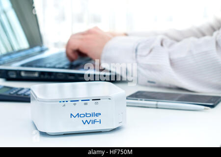 Router mobile device sul tavolo e uomo d affari con computer in background Foto Stock