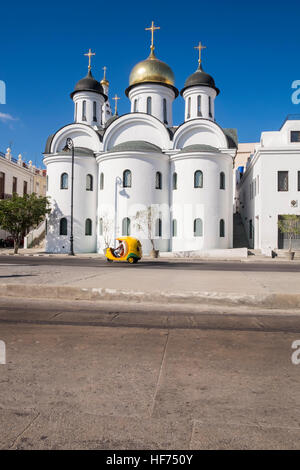 Coco taxi passando cattedrale ortodossa della Madre di Dio di Kazan, La Havana, Cuba. Foto Stock