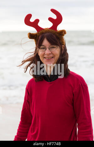 Donna che indossa la renna palchi con archetto prende parte al Bianco Natale carità Dip nuotare a Boscombe, Bournemouth Dorset il giorno di Natale Dicembre Foto Stock