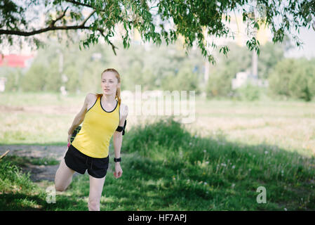 Giovane donna fitness corpo stretching prima di eseguire. Uno sportivo che si leva in piedi sotto la struttura. Foto Stock