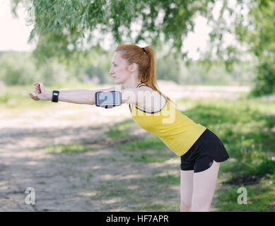 Giovane donna fitness corpo stretching prima di eseguire. Uno sportivo che si leva in piedi sotto la struttura. Foto Stock