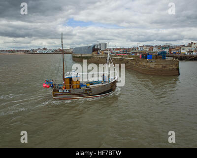 Piccola barca da pesca entrando Bridlington Harbor East Yorkshire Costa, sotto grigio nuvole temporalesche REGNO UNITO Foto Stock