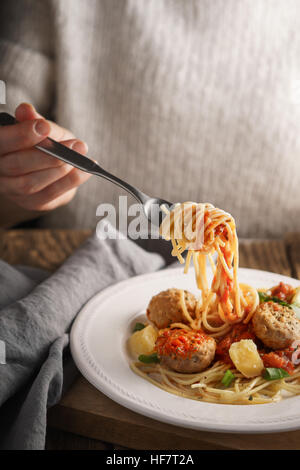 Donna mangiare spaghetti con le polpette di carne e formaggio in verticale Foto Stock