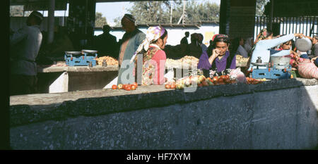 Una fotografia che mostra le persone in uno stand di frutta e verdura a Samarcanda, Uzbekistan, durante l'era sovietica, catturando la cultura del mercato locale e la vita quotidiana nella regione. Foto Stock