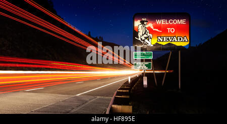 Stato di Nevada line road sign con esposizione a lungo percorsi di traffico di notte. Foto Stock