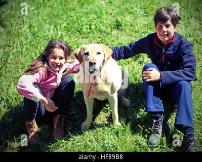 Due bambini con le loro grandi labrador cane sull'erba Foto Stock
