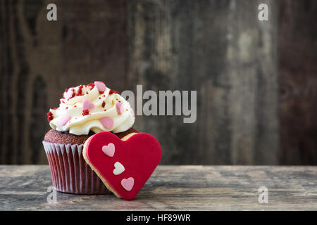 Tortini di San Valentino e cookie con forma di cuore decorata con cuori dolci sul tavolo di legno Foto Stock