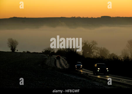 Sunrise a Arundel, UK, 29/12/2016 : Il sole sorge su un congelamento foggy Arun Valley. Il chanctonbury ring può essere visto sul downs che salgono sopra la nebbia come pendolari in viaggio di lavoro sulle strade di seguito. Foto di Julie Edwards/Alamy Live News Foto Stock