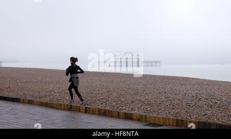 Brighton, Regno Unito. 30 Dic, 2016. Un runner passa al Molo Ovest è avvolta nella nebbia in Brighton Seafront questa mattina come la nebbia e le basse temperature sono state previsioni per il sud dell'Inghilterra oggi © Simon Dack/Alamy Live News Foto Stock