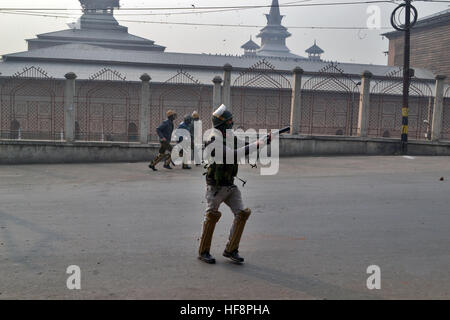 Srinagar Kashmir. 30 Dic, 2016. Un poliziotto si prefigge un gas lacrimogeni, launcher a manifestanti durante una dimostrazione contro contro il govt decisione di rilasciare certificati di domicilio a WPRS e imposizione di SARFAESI atto a Srinagar, Indiano Kashmir amministrato. © Saqib Majeed/Alamy Live News Foto Stock