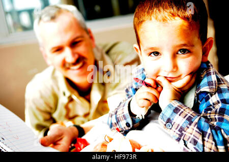 Marina degli Stati Uniti della Cmdr. Gregory Harris i colori con un ragazzo afghano in Indira Gandhi ospedale per bambini masterizzare ward mentre il servizio internazionale membri, anche assegnati alla forza internazionale di assistenza alla sicurezza sede centrale, passare fuori animali imbalsamati e matite colorate per i pazienti ustionati, nel centro di Kabul, Afghanistan, nov. 20. L'ospedale riceva 400 dollari al mese per eseguire tutto il luogo e i bambini masterizzare Ward è un regolare il destinatario di aiuti internazionali portate dai volontari di ISAF. Harris è un personale di comando planner con ISAF. Natale arriva presto e spesso per quelli a Indira Gandhi Institute o Foto Stock