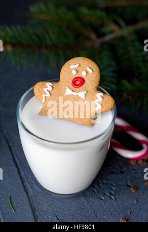 Gingerbread Man cookie che affonda in un bicchiere di latte. Vacanze di Natale il cibo, l'inverno e l'anno nuovo concetto Foto Stock